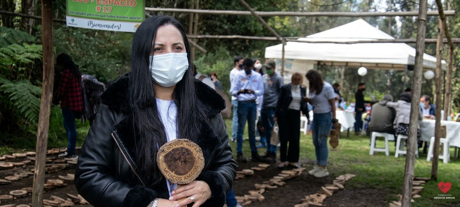 Participante sostiene una placa de madera con la frase Hubo vida, hay amor, Médicos Amigos